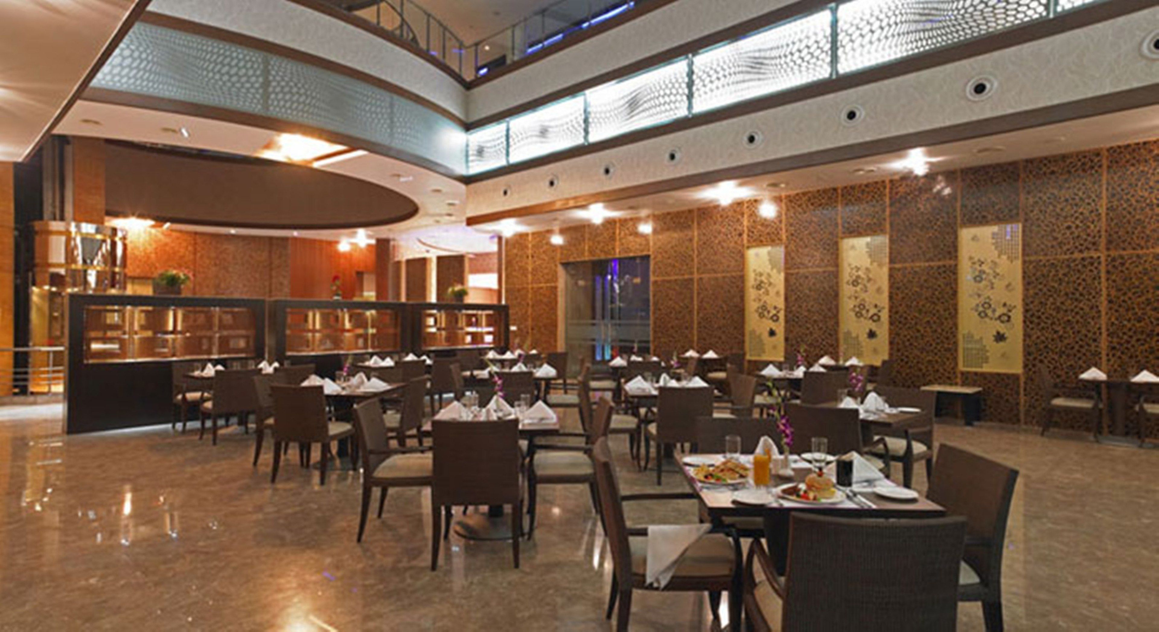 Ein geräumiges Restaurant mit mehreren Tischen, Stühlen, einer Theke und dekorativen Wandverkleidungen.