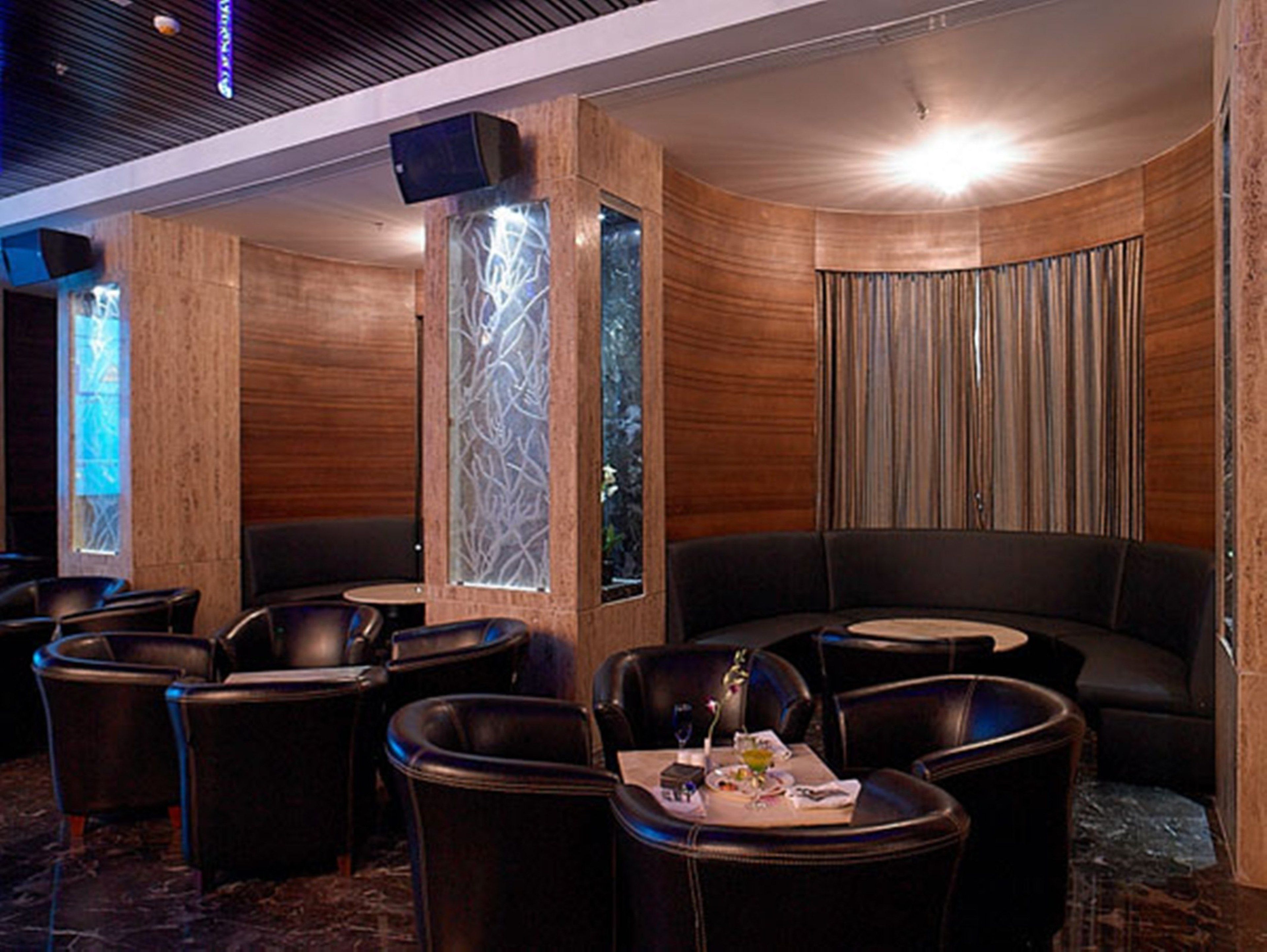 A modern lounge area with leather seating, a glass partition, and a wooden wall.