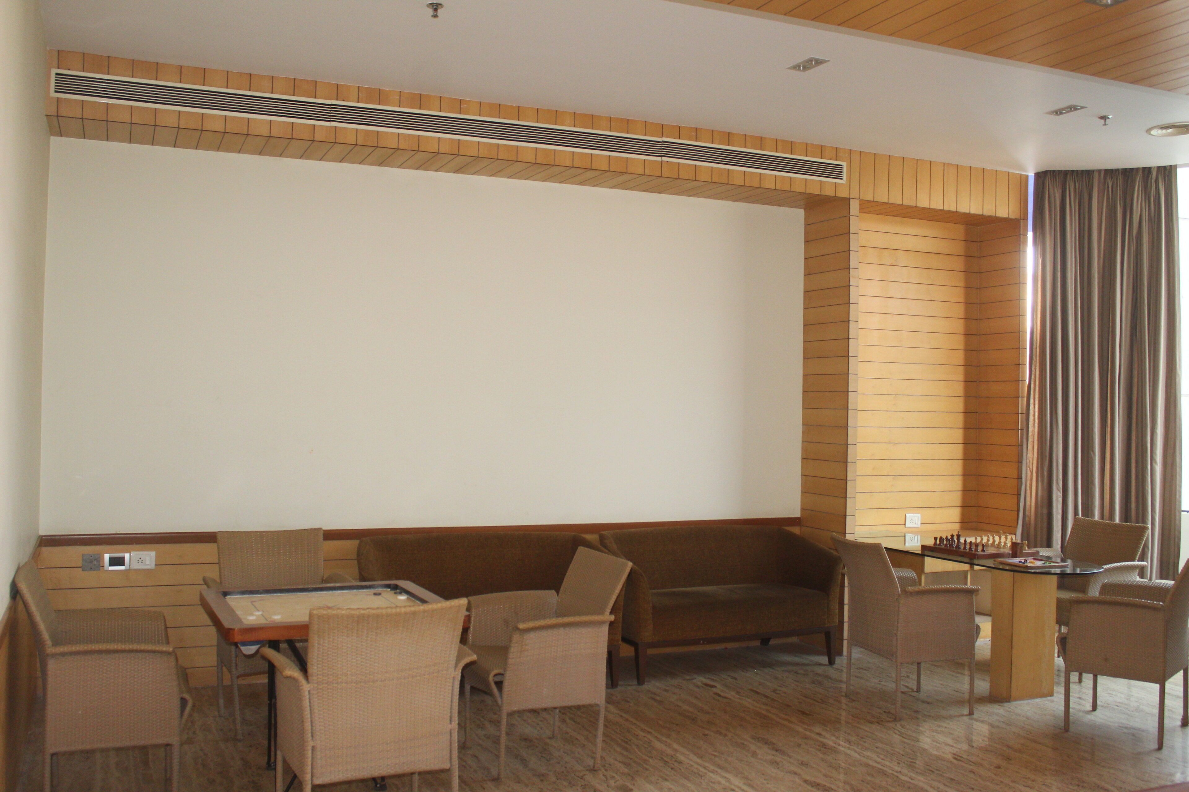 A hotel room with a wooden ceiling, a sofa, a dining table, and a chess table.