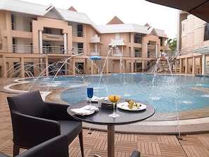 A pool area with a table and chairs, surrounded by a building with multiple balconies.