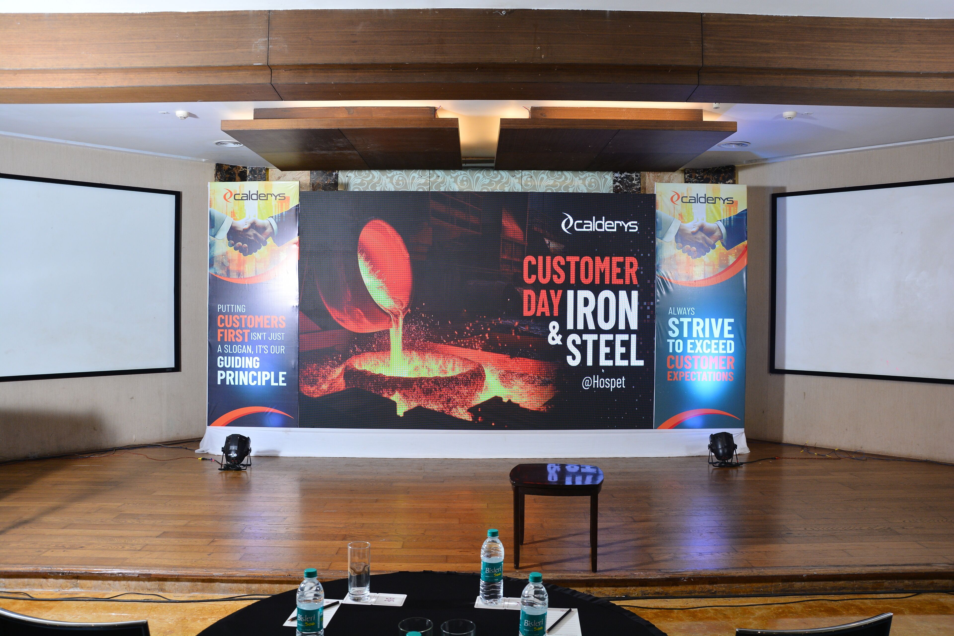 A conference room with a stage, a podium, and a large screen displaying a presentation.