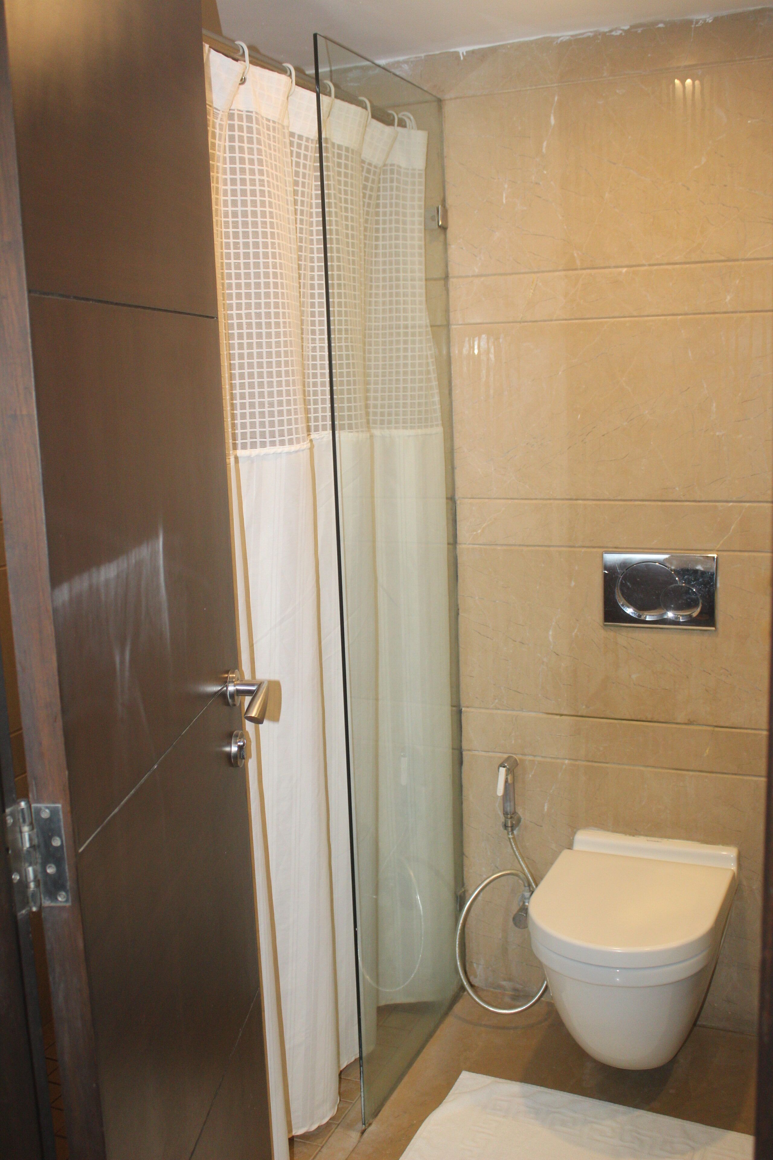 A bathroom with a shower, toilet, and a glass door.