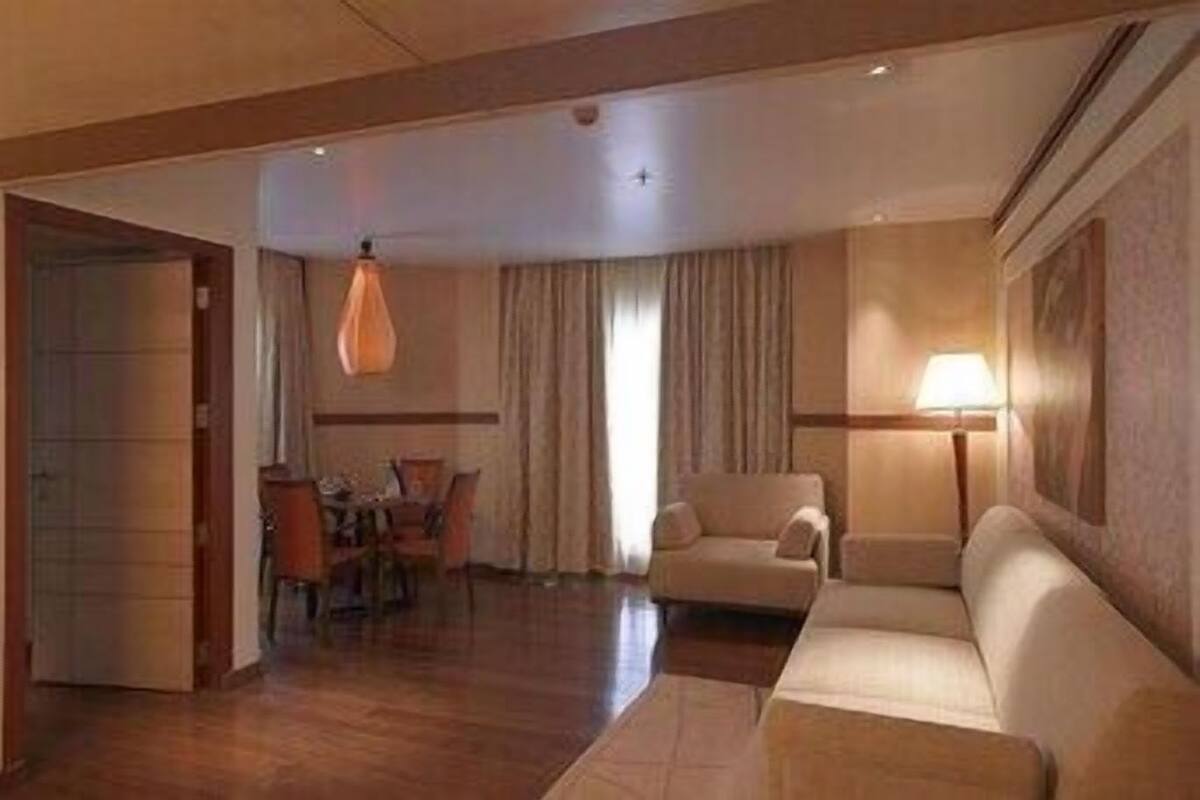 Une chambre d’hôtel avec un coin repas, un canapé, une lampe et une porte.