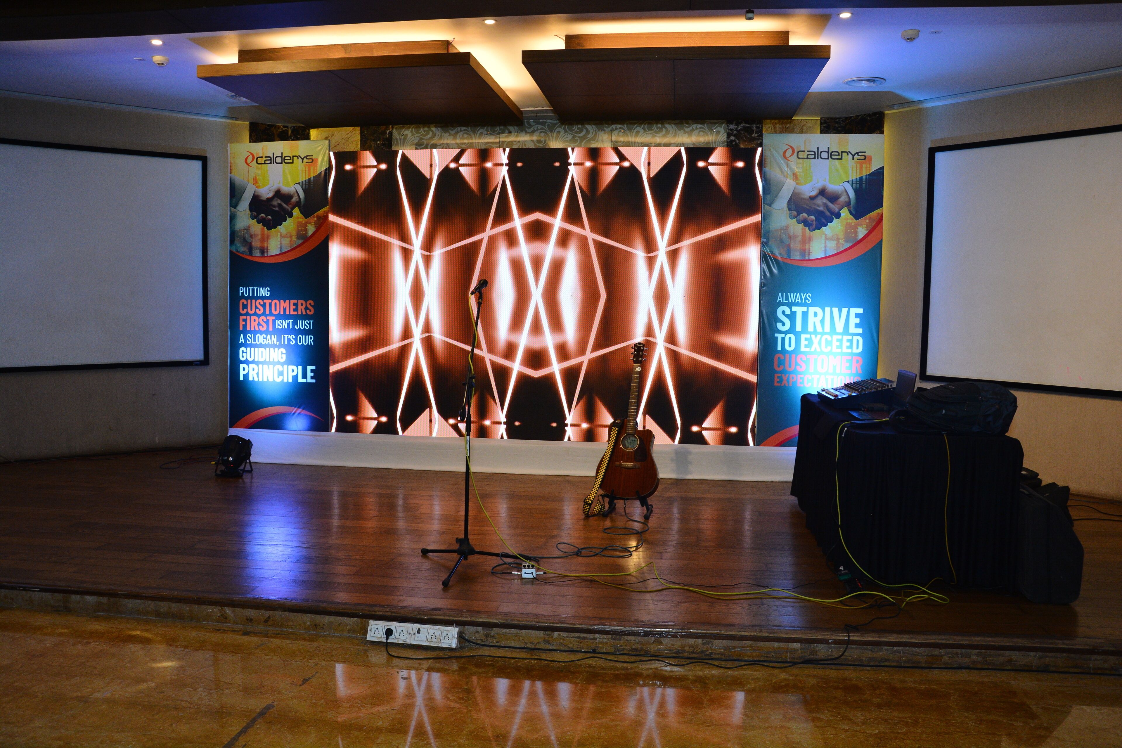 A stage with a guitar, a microphone stand, and promotional banners.