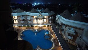 Un hotel con una piscina grande, varios balcones y un exterior bien iluminado.