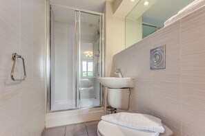 A modern bathroom with a glass-enclosed shower, a white sink, and a toilet with a white towel. - Roomzzz Leeds Headingley (Leeds)