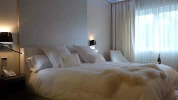 Habitación de hotel con una cama grande, dos lámparas de noche, un teléfono y una botella de champán sobre la mesita de noche.
