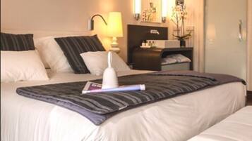 Una habitación de hotel con cama, mesita de noche, lámpara y espejo.