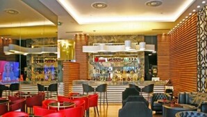 Een bar met rode stoelen en een toog.