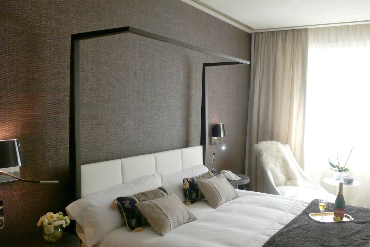 Une chambre d’hôtel avec un grand lit, un téléviseur à écran plat, une table de chevet avec une lampe et une vue sur l’extérieur par la fenêtre.