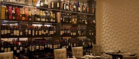 Un restaurante con bodega de vinos, mesas dispuestas para comer y una pared con diseño.