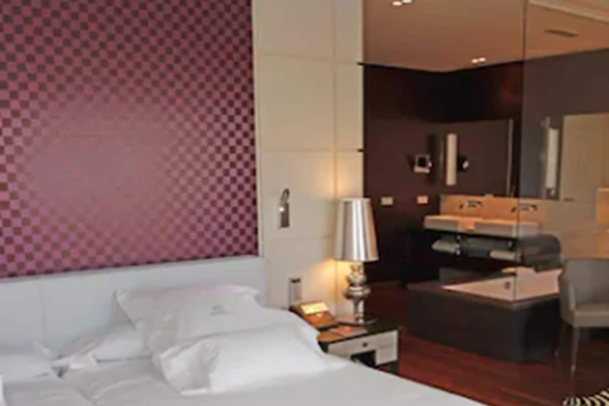 Une chambre d’hôtel avec un grand lit, un bureau, une chaise et une petite table.