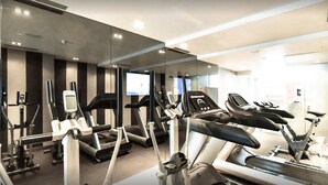 Een sportschool met diverse cardioapparaten, waaronder loopbanden en elliptische trainers, in een ruim opgezette indeling.