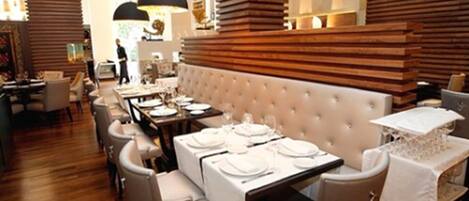 Un restaurante con un amplio comedor, paneles de madera e iluminación colgante moderna.