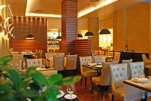 A restaurant with multiple dining tables and chairs, a bar area, and a modern interior design.