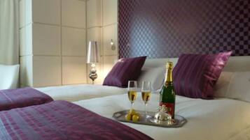 Habitación de hotel con cama, dos almohadas, una bandeja con champán, vasos y limones.