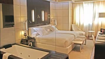 A hotel room with a large bed, a separate sofa, a small table, and a bathtub.