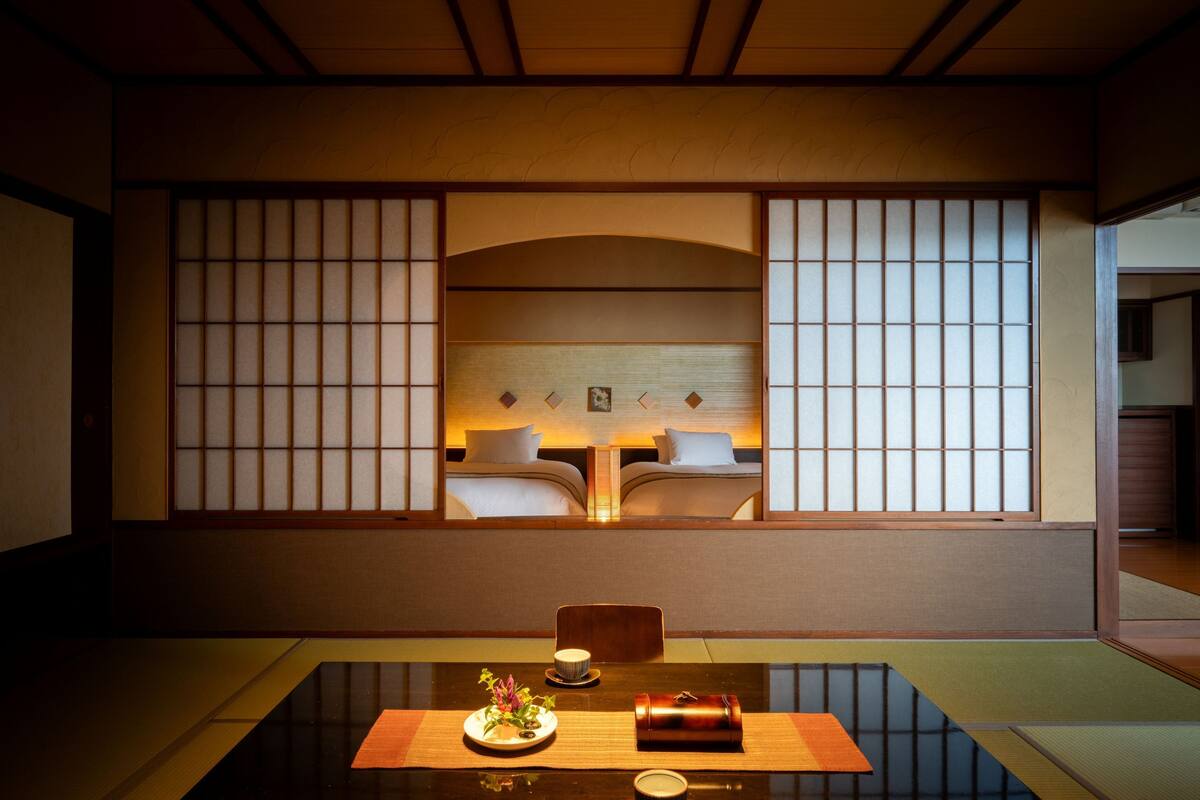 Ett traditionellt japanskt rum med tatamimattor på golvet, ett lågt bord med en kudde och en skjutdörr med shojipaneler.