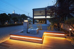 Una entrada de hotel moderna con una terraza de madera, una jardinera de piedra y un letrero que indica Takinoyu Hotel.