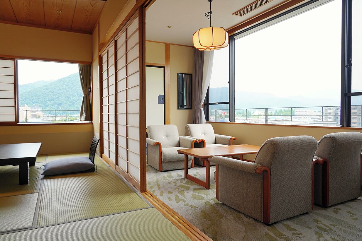 Una habitación tradicional japonesa con suelo de tatami, una mesa baja y un conjunto de sofás.