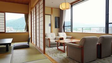 Una habitación tradicional japonesa con suelo de tatami, una mesa baja y un conjunto de sofás.