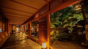 A corridor with traditional wooden architecture, a koi pond, and lanterns. - Tendo Onsen TAKINOYU (Tendo)