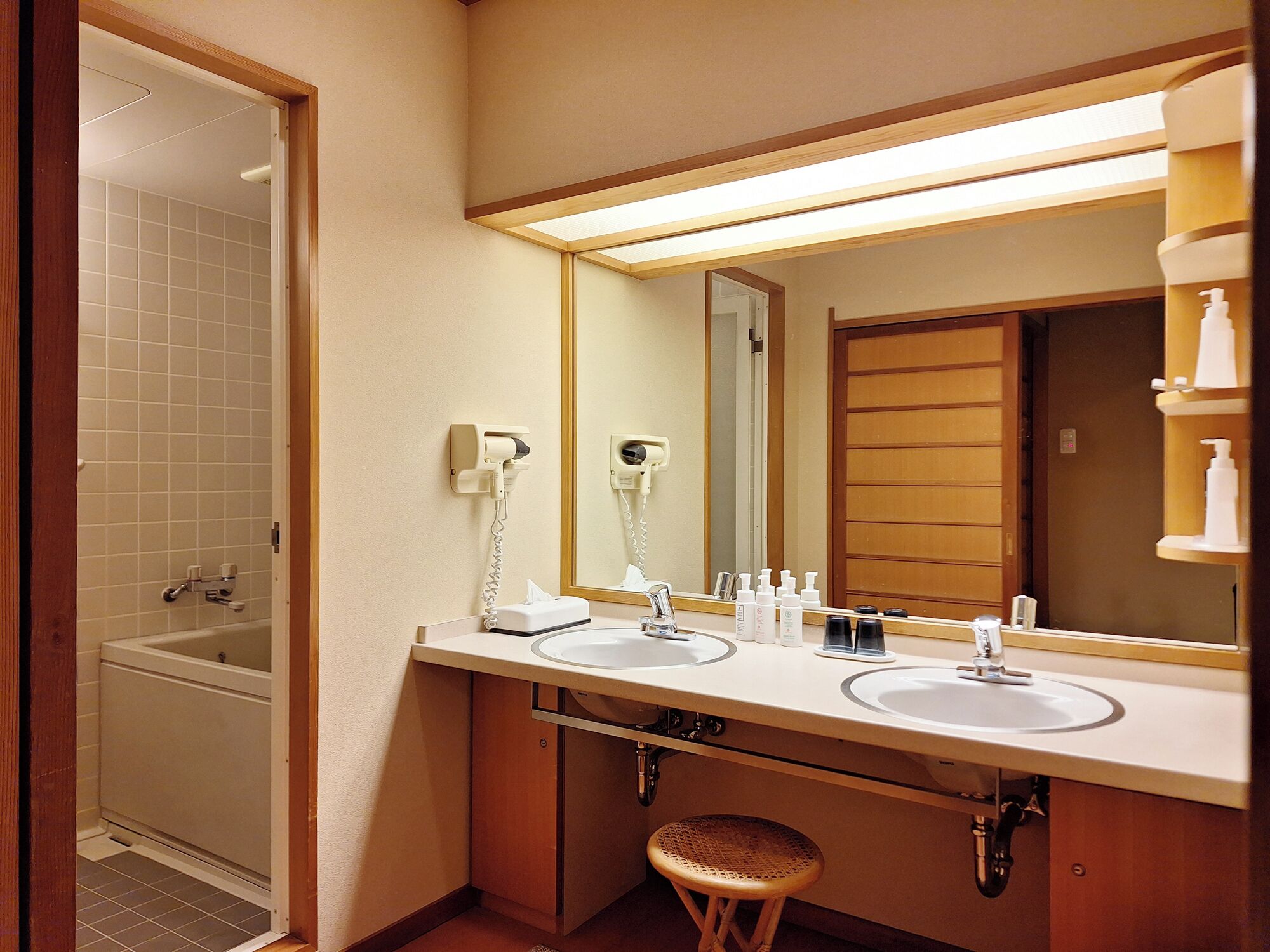 Une salle de bain d’hôtel équipée de deux lavabos, d’un miroir, d’un sèche-cheveux et de toilettes.
