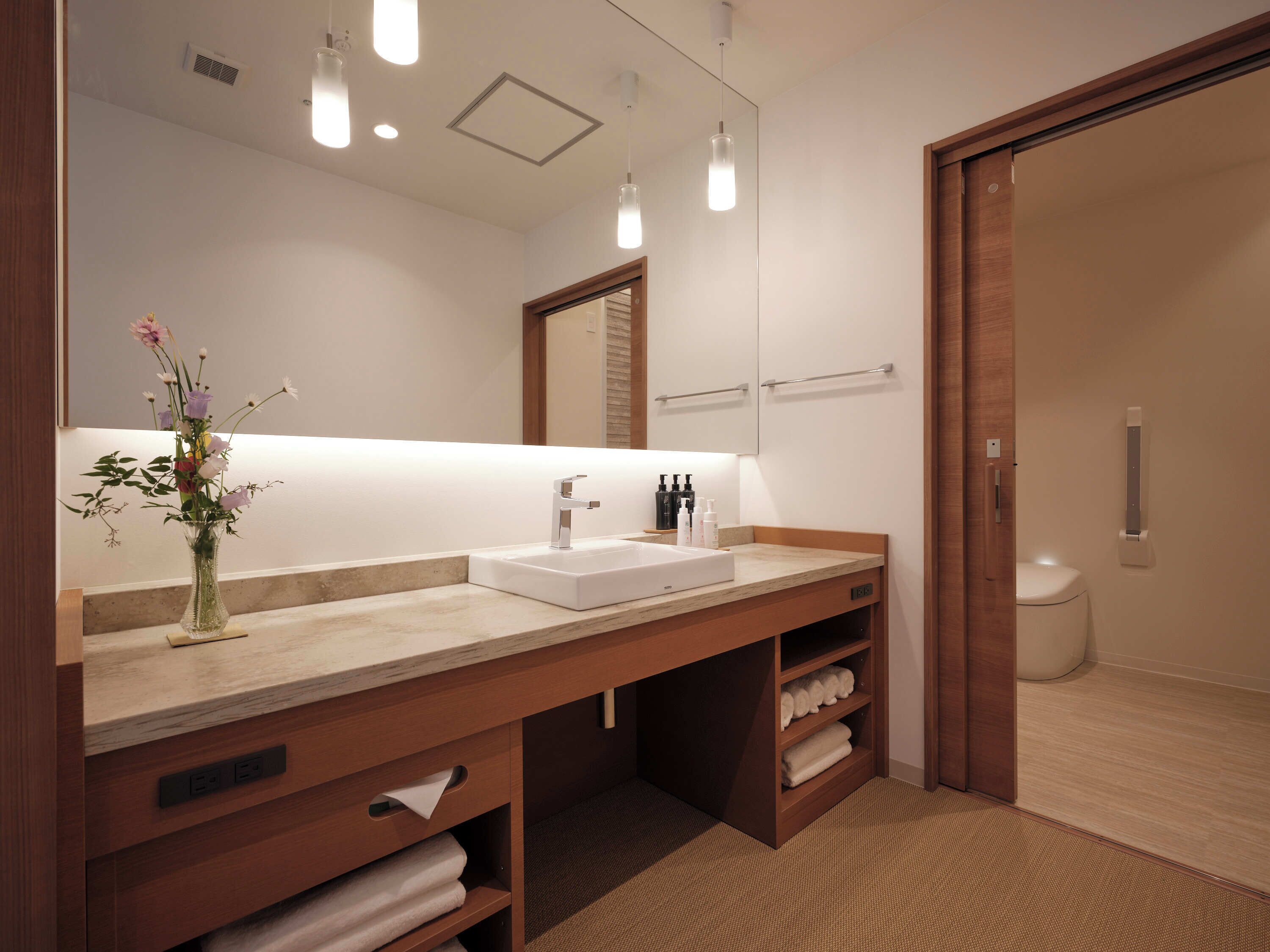 A modern bathroom with a large mirror, a sink, and a shower area.