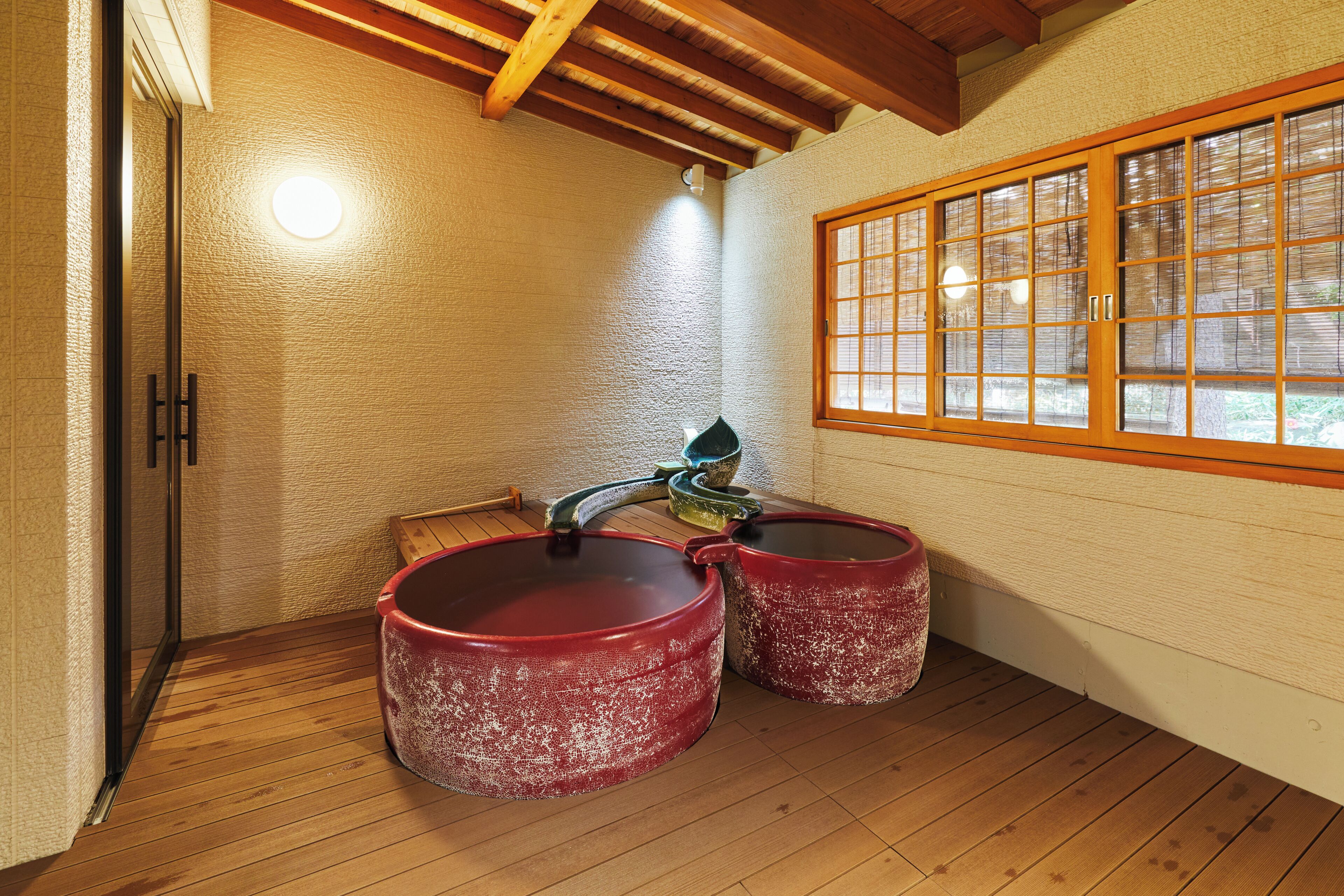 Una habitación tradicional japonesa con suelo de tatami, techo de vigas de madera y ventana con marcos de madera.