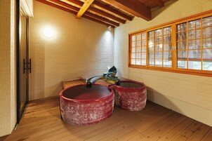 Una habitación tradicional japonesa con suelo de tatami, techo de vigas de madera y ventana con marcos de madera.