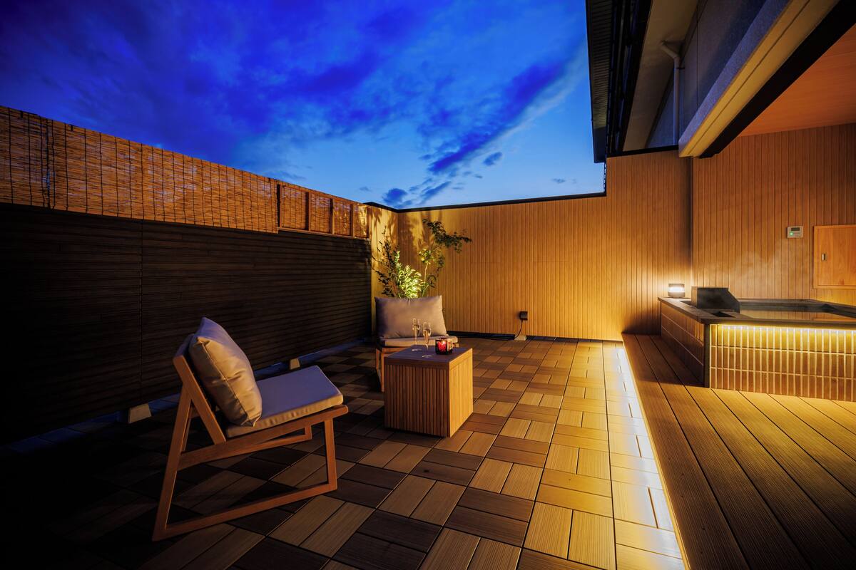 Ett trädäck med en solstol och ett tillhörande fotstöd, ett bubbelbad och utsikt över himlen.