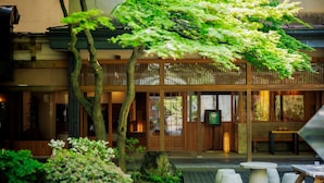 A traditional Japanese building with a wooden exterior, a balcony, and a stone pathway leading to a seating area. - Tendo Onsen TAKINOYU (Tendo)