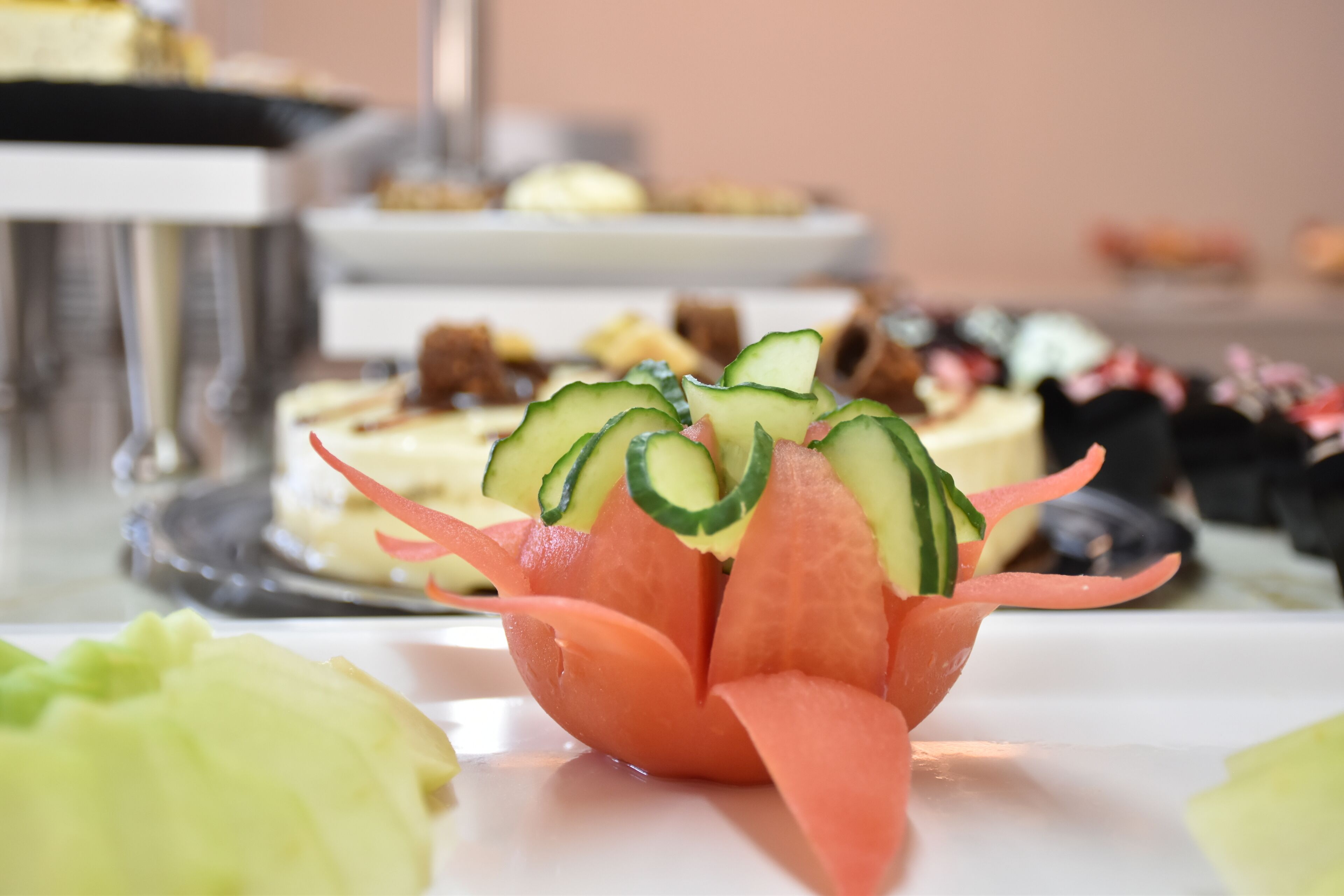 A dessert table with various sweet treats and a centerpiece of a watermelon flower arrangement.