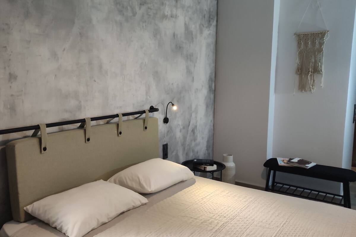 A bedroom with a bed, bedside table, lamp, and wall decor.