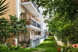 Een meerlaags gebouw met balkons, een tuin met bloemen en een houten sierhekwerk.