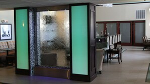 Eine Lobby mit Wasserspiel, Sitzgelegenheiten und einer Rezeption.