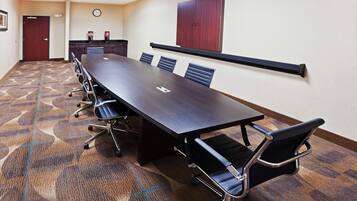 A conference room with a long table, six chairs, a clock, and a cabinet.