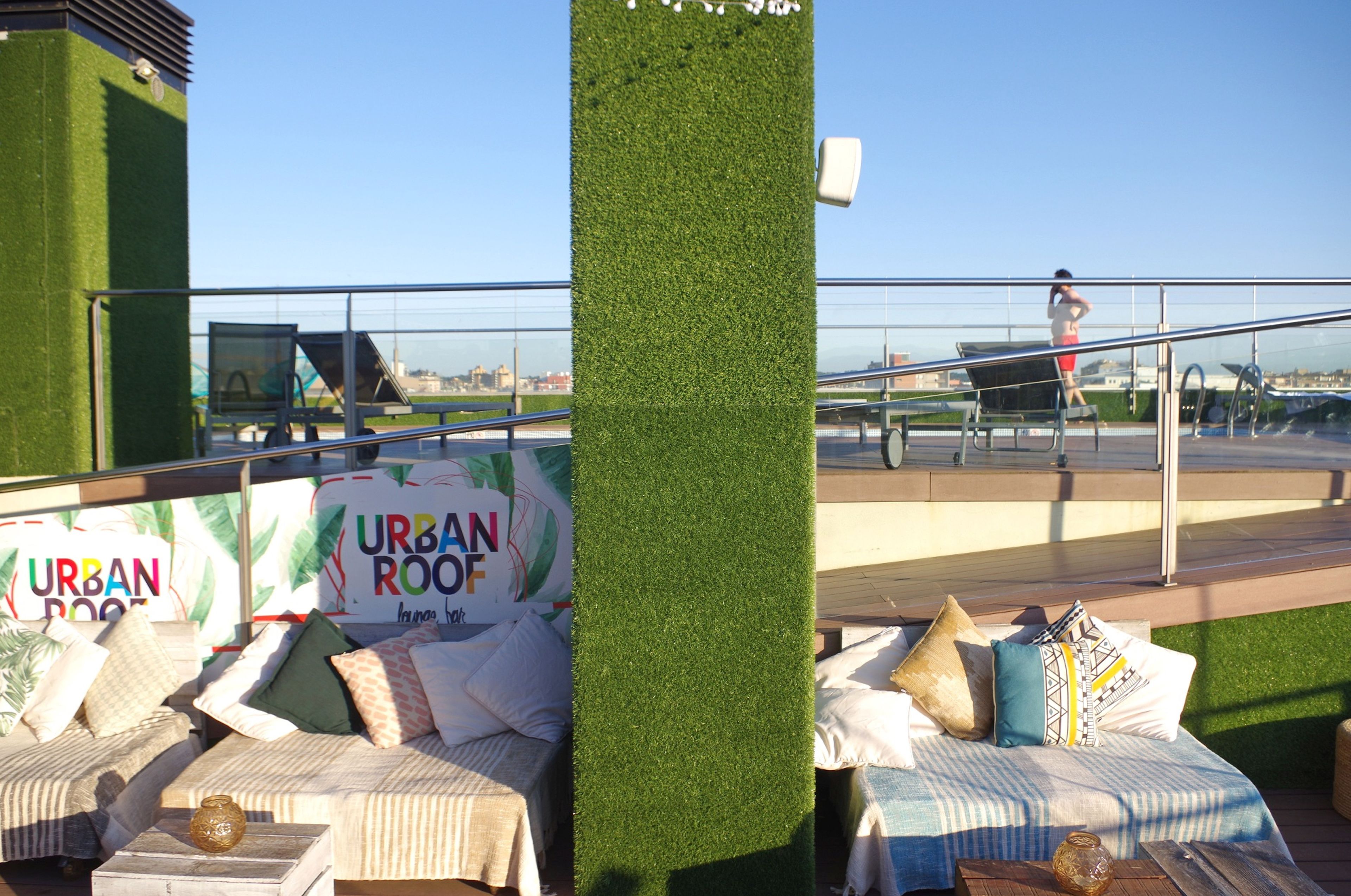 A rooftop lounge area with seating arrangements and a sign reading "URBAN ROOF".