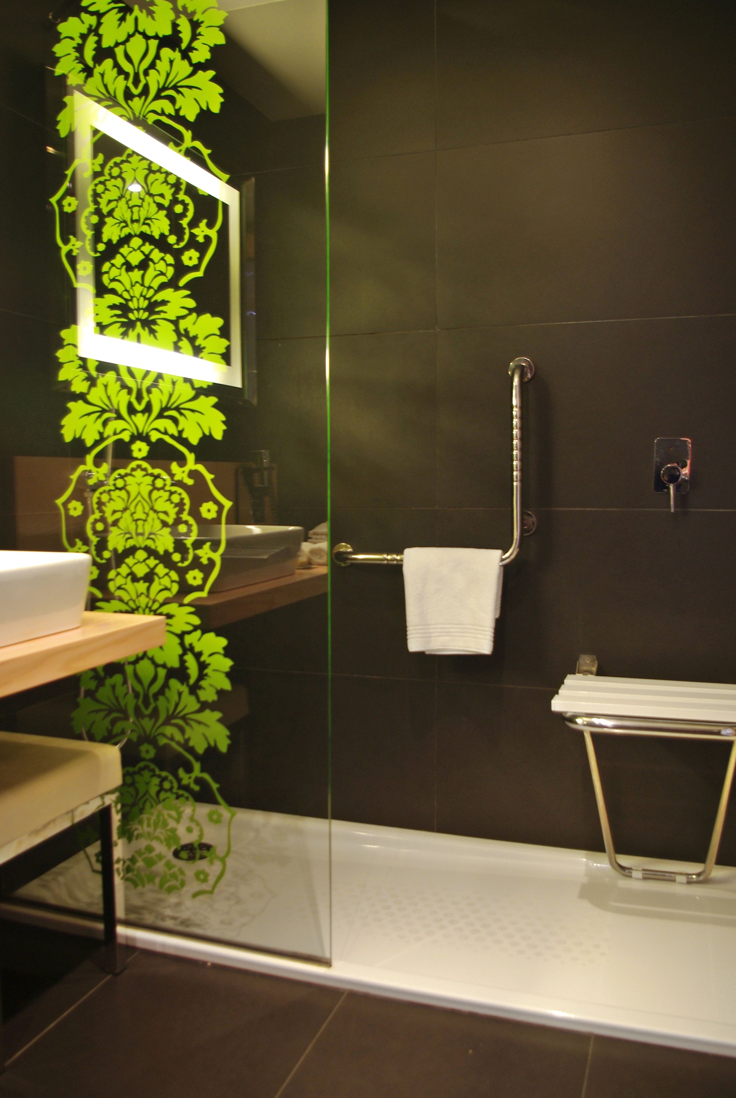 Un baño con cabina de ducha de vidrio, lavabo blanco, espejo y toallero.