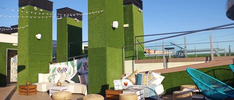 Um terraço no telhado com uma parede de grama sintética verde, assentos externos e uma vista desobstruída do céu.