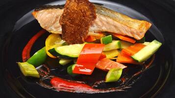 Un plato con salmón, verduras y salsa.