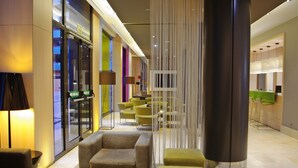 A modern lobby with seating areas, a reception desk, and a glass facade. - DoubleTree by Hilton Hotel Girona (Girona)
