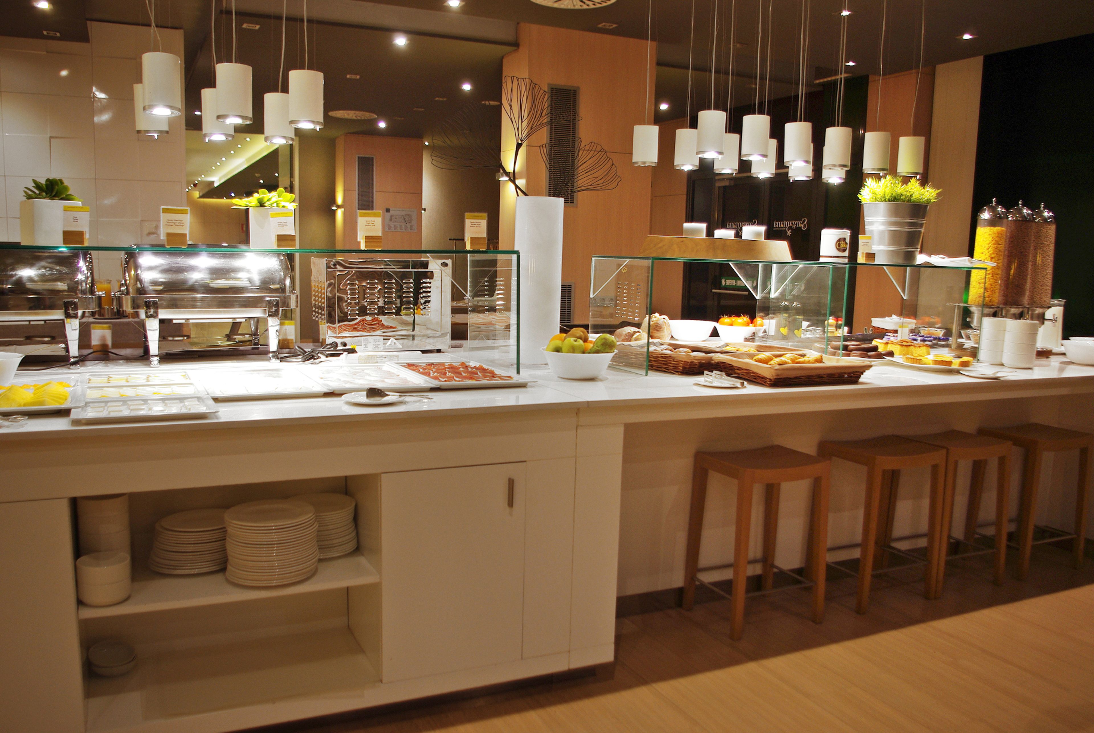 A buffet setup with various food items, a glass display case, and hanging light fixtures.