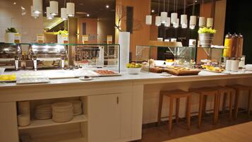 A buffet setup with various food items, a glass display case, and hanging light fixtures.