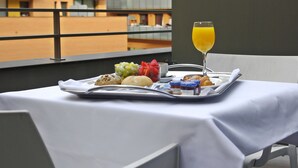 A tray with breakfast items and a glass of orange juice on a table with a white tablecloth, overlooking a building with balconies. - DoubleTree by Hilton Hotel Girona (Girona)