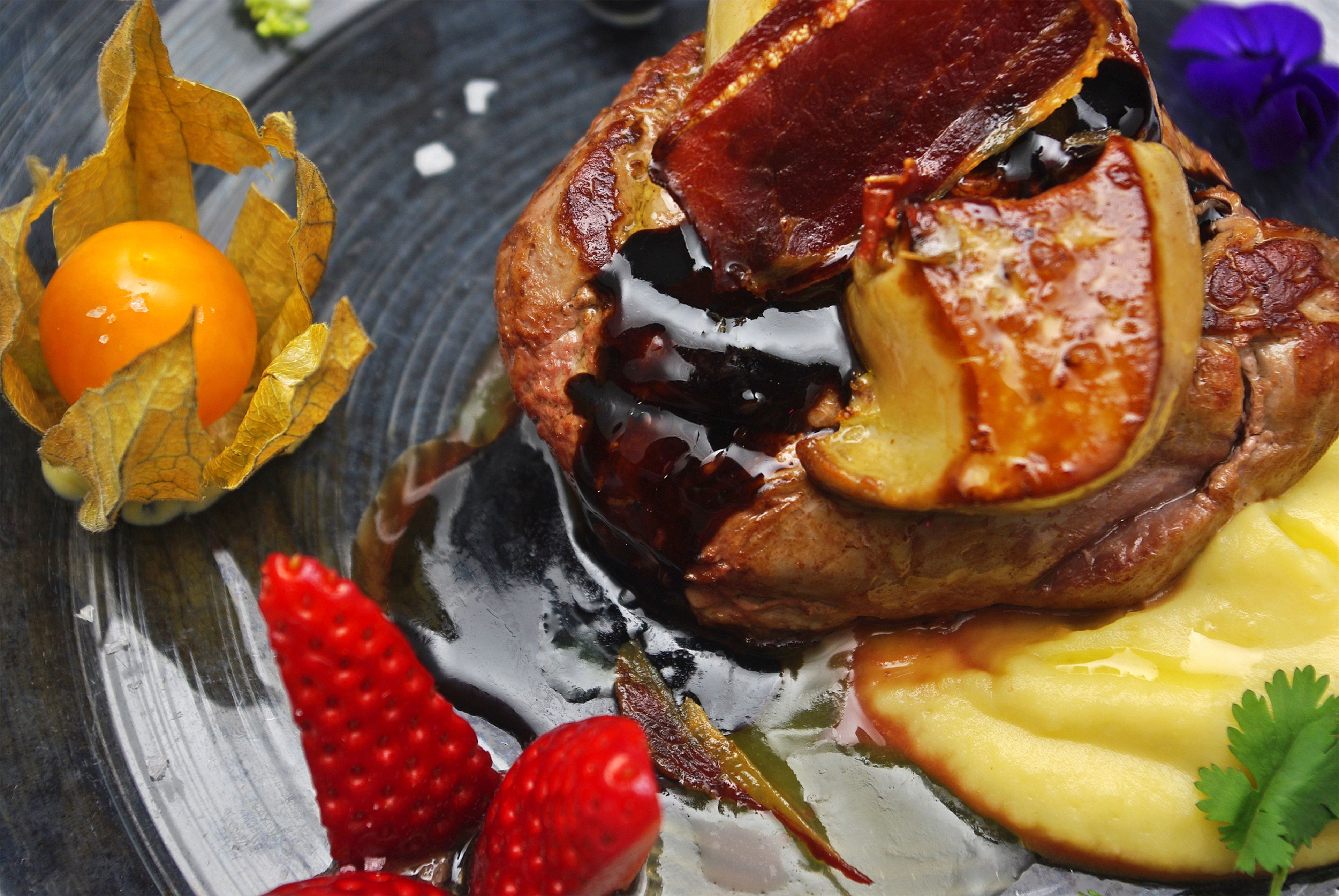 A dessert plate with a baked dish, fruit, and a small bowl of fruit.