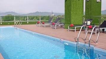 A swimming pool with lounge chairs and a view of the mountains.