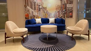 A modern living room with a blue sofa, two beige armchairs, and a round coffee table.