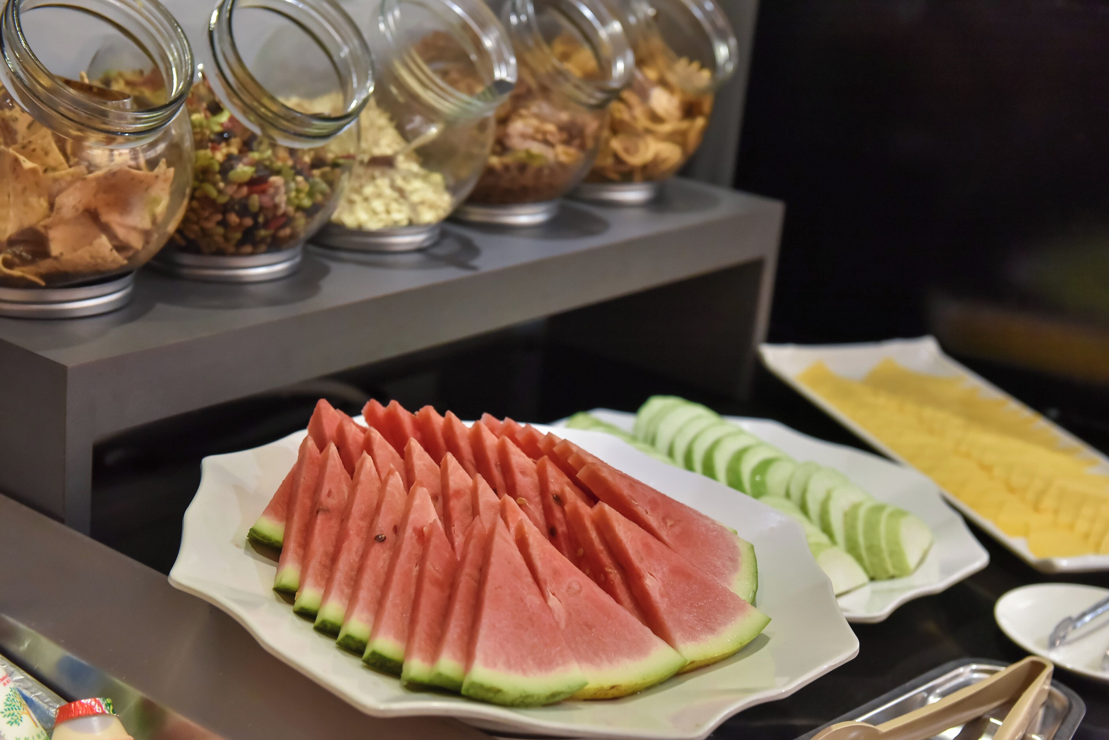 A buffet with various food items including sliced watermelon and cucumbers.