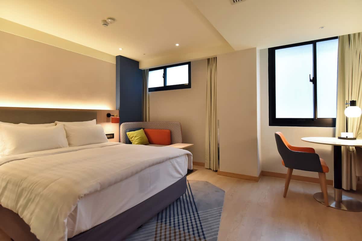 Een hotelkamer met een groot bed, een bureau en een stoel.